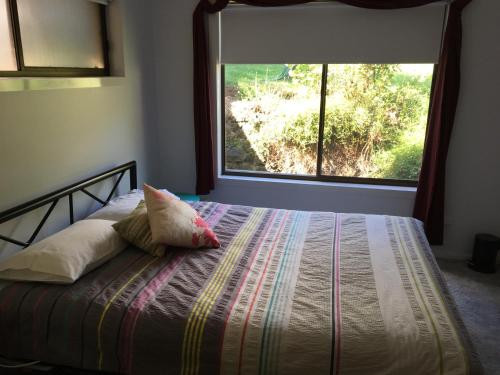 Un dormitorio con una cama con una ventana grande. en The Greenery, en Castlemaine