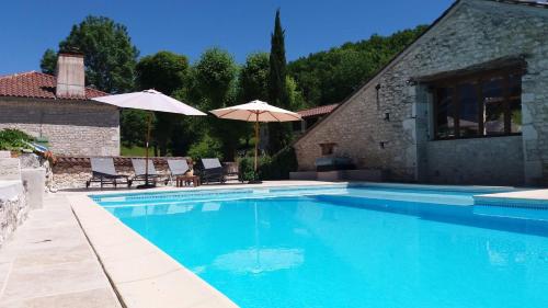a swimming pool with chairs and umbrellas next to a house at B&B Culinaire La Mouline - adults only in Belvèze