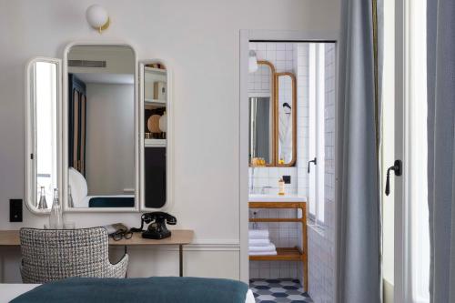 a bedroom with a bed and a desk and two mirrors at Hotel Louvre Montana in Paris