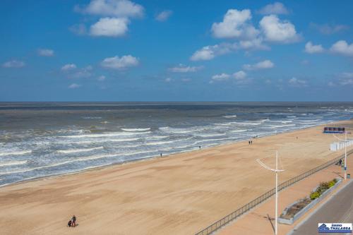 a beach with people walking on the sand and the ocean at Atlantic 0504 in Koksijde