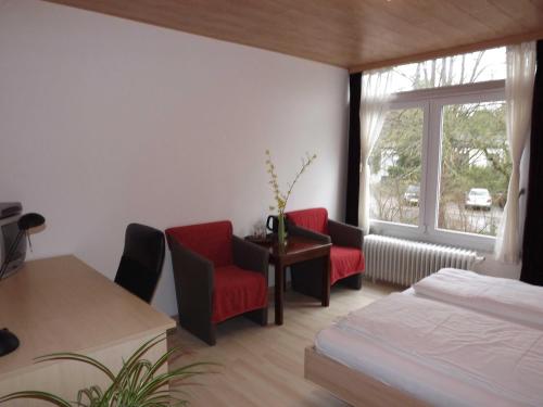 a bedroom with two red chairs and a bed and a window at Private Übernachtung in Kempten