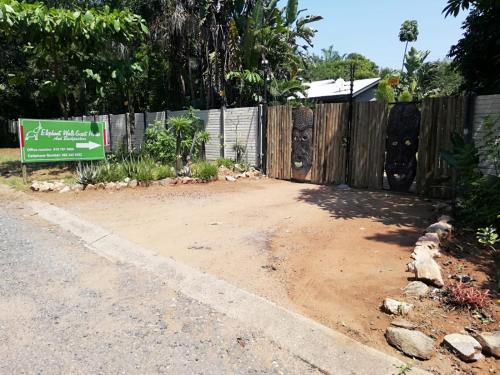 a fence next to a dirt road with a sign at Elephant Walk Guesthouse and Back Packers in Phalaborwa