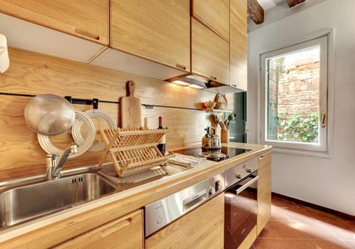 uma cozinha com um lavatório de aço inoxidável e armários de madeira em Cà Malvasia House With Garden em Veneza