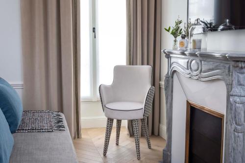 a white chair sitting next to a fireplace at Hotel Louvre Montana in Paris
