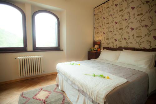a bedroom with a large bed with two windows at Villa La Ginestra - Charming Country Home in Capolona