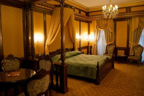 a bedroom with a canopy bed and a table and chairs at Hotel Casa Capsa in Bucharest