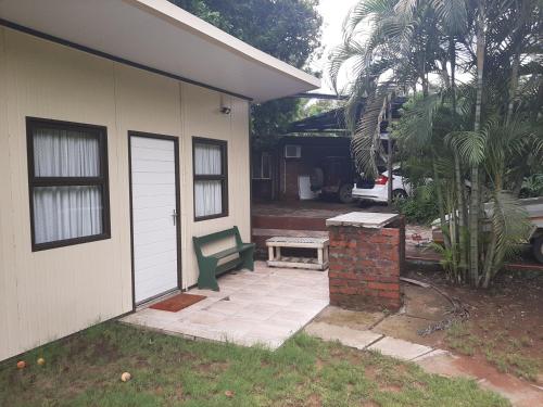 a house with a patio with a green bench next to it at Elephant Walk Guesthouse and Back Packers in Phalaborwa