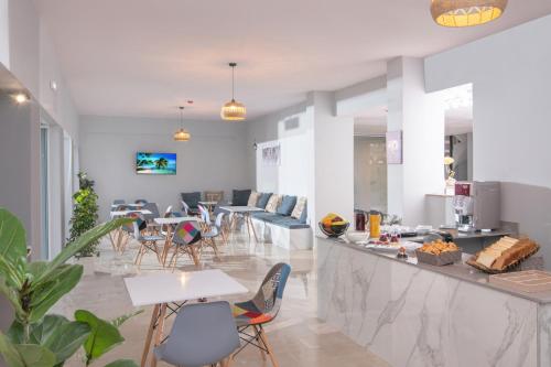 a room with tables and chairs and a counter with a kitchen at Golden Sunlight Hotel by Estia in Gouves