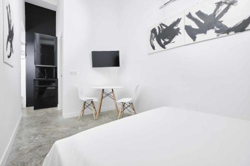 a white bedroom with a table and two chairs at FERIA MODERN y LUXURY in Seville