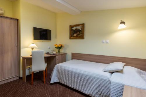 a bedroom with a bed and a desk and a chair at U Pana Cogito in Kraków