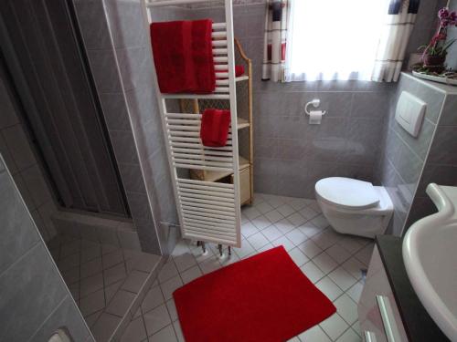 a bathroom with a white toilet and red towels at Flattach Apartment 3 in Ausserfragant