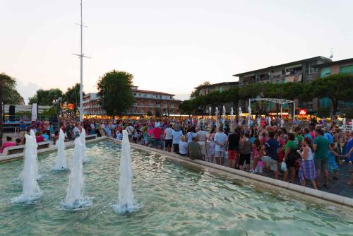 ビビオーネにあるApartments in Bibione 24391の噴水の周りに立つ大勢の人々