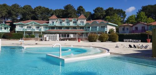 a swimming pool in front of a large building at Lacanau golf in Lacanau