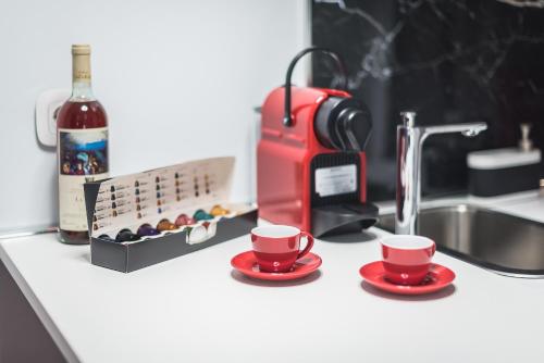 - une cafetière rouge et deux tasses rouges sur un comptoir dans l'établissement Iguana Gold Luxury Suites 1min from Ermou str, à Athènes