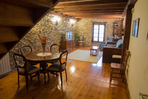 a living room with a table and chairs and a stone wall at Casa Rural-Apartamentos Zelaikoa in Zestoa