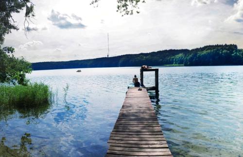 a couple sitting on a dock on a lake at Rancho Zapotoczny in Łagów