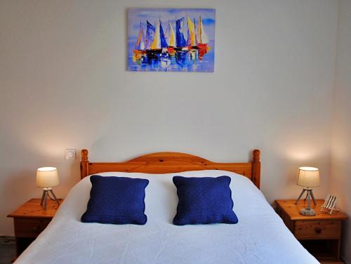 ein Schlafzimmer mit einem Bett mit zwei blauen Kissen in der Unterkunft Maison de vacances à 10min des plages et de la Tranche sur Mer in La Jonchère