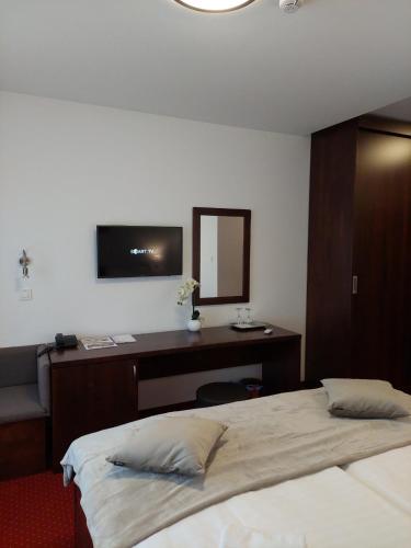a bedroom with a bed and a desk and a mirror at Hotel Orion in Ivanec