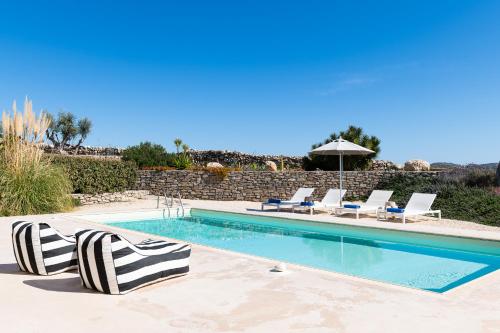 a swimming pool with two lounge chairs and an umbrella at Parasporos Villa - Private Pool - Beach Access in Parasporos