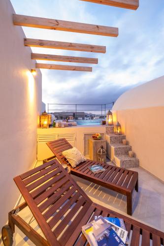 a balcony with two wooden benches and a view of the ocean at MILESTONE VILLAS in Megalokhori