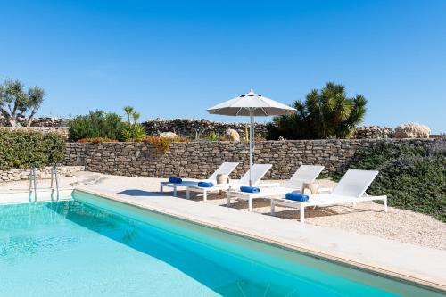 a group of chairs and an umbrella next to a swimming pool at Parasporos Villa - Private Pool - Beach Access in Parasporos