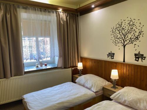 a bedroom with two beds and a tree on the wall at G Penzion in Spišská Belá