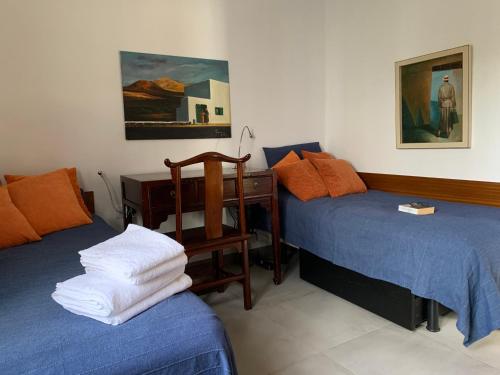 a bedroom with two beds and a desk with towels at Pequeño Paraíso Lanzarote, modernes Ferienhaus am Meer für 4 in Playa Honda