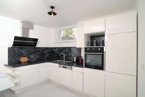 a white kitchen with black and white appliances at Designapartments Business and More - Sennhütte 9 in Wernigerode