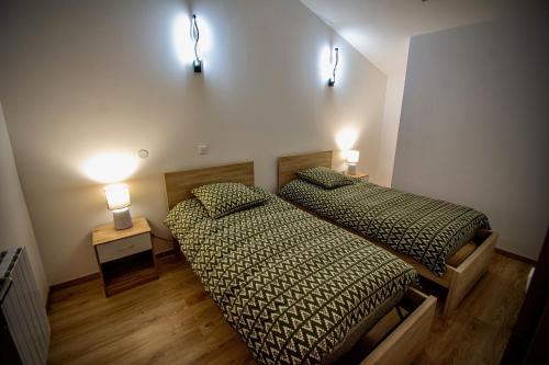 two beds in a room with two lights on the wall at Gîte de Léonie Moulin de Tartay en Avignon in Avignon