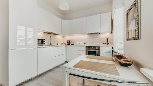 eine weiße Küche mit weißen Schränken und einem Tisch in der Unterkunft Spacious - 140 square meters Apartment, Vilnius City Centre in Vilnius