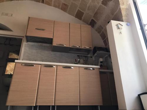 una cocina con armarios de madera en una habitación en GRAZIOSO MONOLOCALE NEL CUORE DEL CENTRO STORICO, en Francavilla Fontana