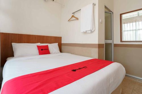 a bedroom with a large bed with a red blanket on it at RedDoorz near Plaza Botania 1 Batam in Batam Center
