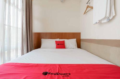 a bed with a red pillow on it in a room at RedDoorz near Plaza Botania 1 Batam in Batam Center