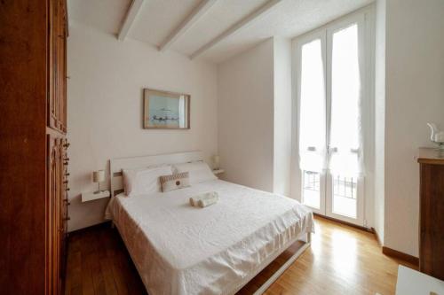 una camera bianca con un letto e una grande finestra di La finestra sul lago, appartamento in pieno centro a Laveno