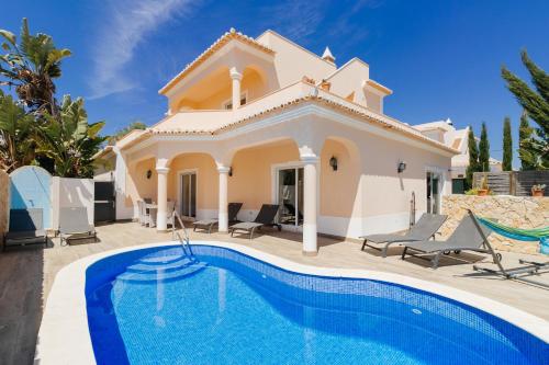 a villa with a swimming pool in front of a house at Casa Vista Mar in Carvoeiro