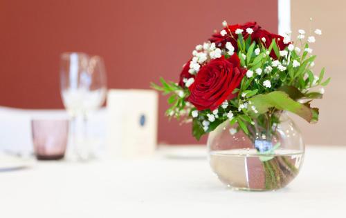 a vase with a red rose sitting on a table at Hotel Puerta de Bilbao in Barakaldo