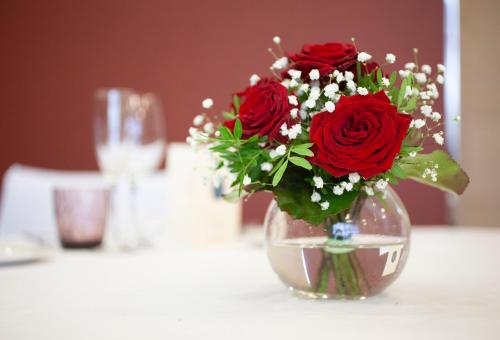 a vase filled with red roses sitting on a table at Hotel Puerta de Bilbao in Barakaldo