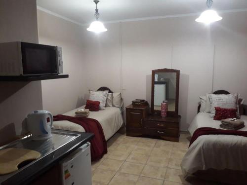 um quarto de hotel com duas camas e uma televisão em KIHARA GUESTHOUSE em Bethlehem