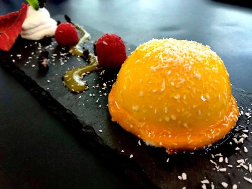 a piece of cake with an orange on a black plate at Novotel Pau Pyrénées in Lescar