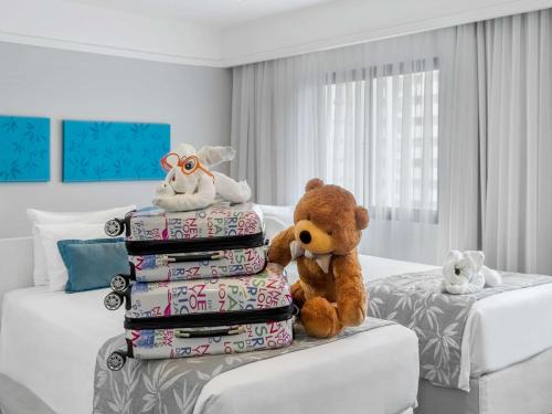 a teddy bear sitting on top of a bed in a room at Mercure Sao Paulo Ibirapuera Privilege in São Paulo