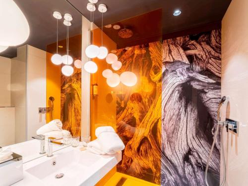 a bathroom with a large painting on the wall at Mercure Valence in Valence