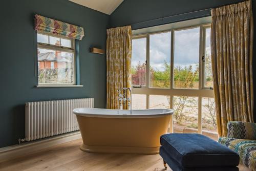 a bathroom with a tub and a large window at Snipe Barn in Aston