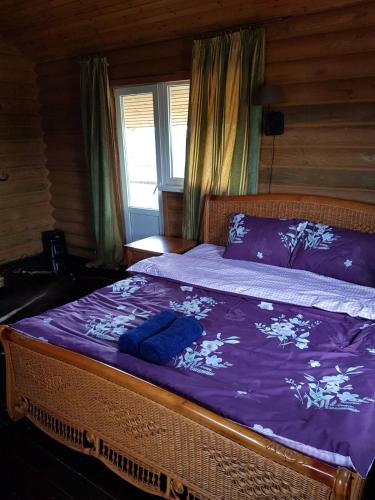 Un dormitorio con una cama con sábanas moradas y una ventana en Загородный дом , сруб , рыбалка , баня , отдых , река , лес, en Troitskoye