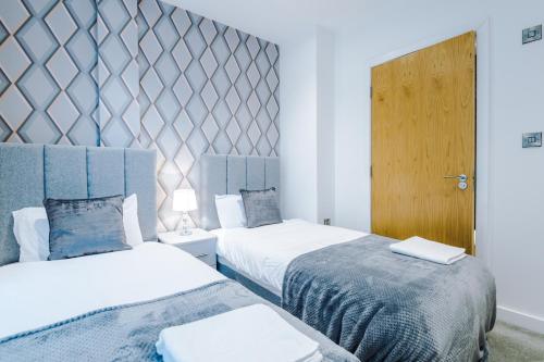 1 dormitorio con 2 camas y puerta de madera en The Popworks 2 Bedroom Apartment - MCR Dens en Mánchester
