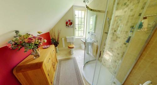 a bathroom with a shower and a vase of flowers at Rock House Cottage in Exeter