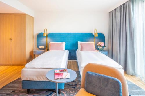 a hotel room with two beds and a couch at Capri by Fraser Leipzig in Leipzig