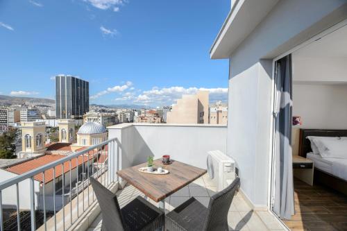 een balkon met een tafel en stoelen en uitzicht op de stad bij Piraeus City Hotel in Piraeus