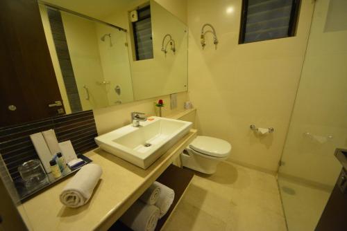 a bathroom with a sink and a toilet and a mirror at The Legend Inn @Nagpur in Nagpur