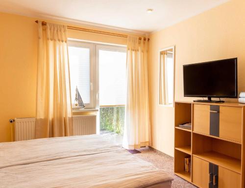 um quarto com uma cama, uma televisão e uma janela em Ferienwohnungen Bergenblick em Gademow