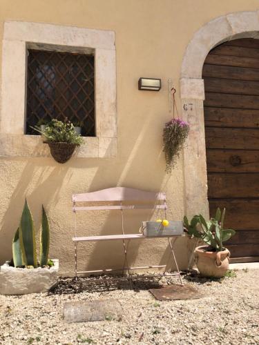 a pink chair next to a building with potted plants at Dimora dell'Arte-CantinArte in Navelli